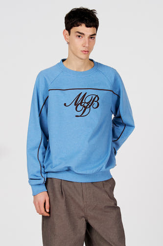 Pull bleu à col rond de Le Fabuleux Marcel de Bruxelles, vu de dos, avec un pantalon marron.