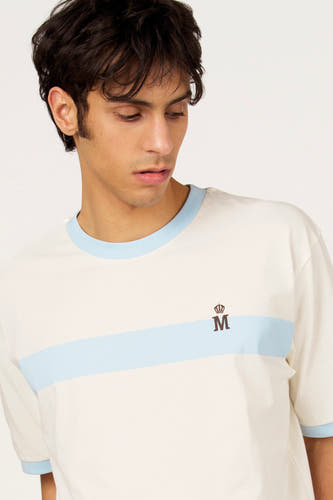 T-shirt blanc à manches courtes de Le Fabuleux Marcel de Bruxelles, avec bande bleu clair et 'M' marron avec couronne.