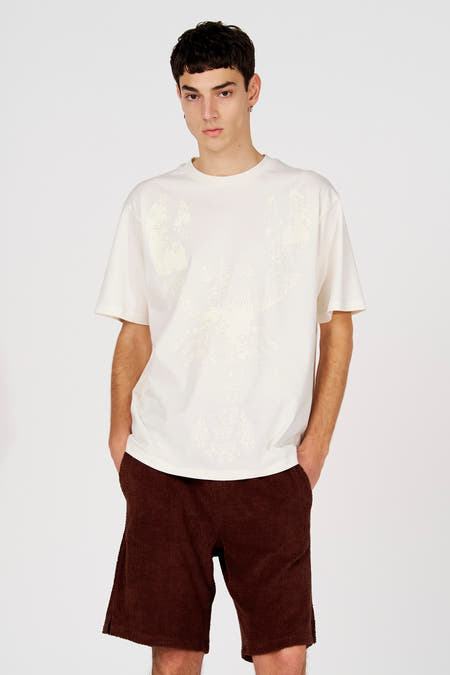 Wit T-shirt met korte mouwen van Le Fabuleux Marcel de Bruxelles, met een grote kreeftprint vooraan, gecombineerd met bruine shorts.
