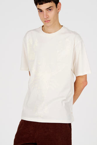 T-shirt blanc (manches courtes) de Le Fabuleux Marcel de Bruxelles, avec un motif graphique sur le devant, combiné avec un pantalon marron.