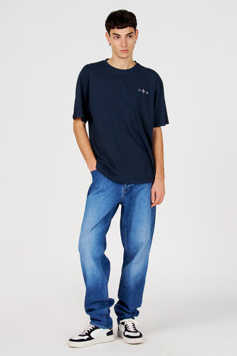 T-shirt bleu à manches courtes de Le Fabuleux Marcel de Bruxelles, porté avec un jean et des baskets.