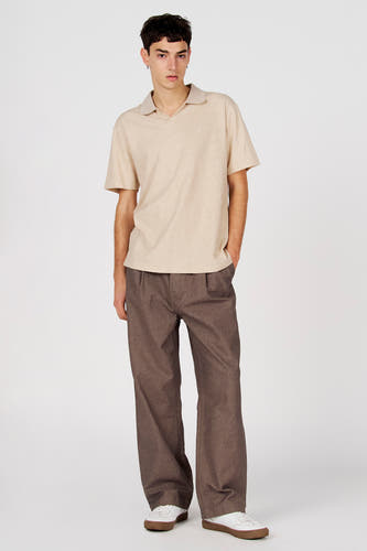 Polo grise de Le Fabuleux Marcel de Bruxelles, à manches courtes et portée avec un pantalon marron et des baskets blanches.
