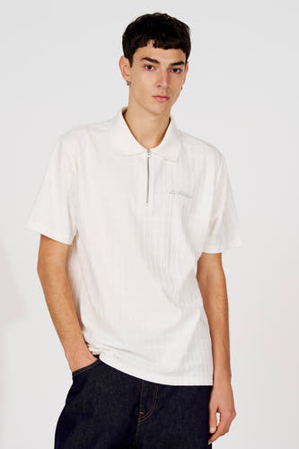 Polo blanc de Le Fabuleux Marcel de Bruxelles, avec motif à carreaux subtil, vu de dos, combiné avec un jean foncé.