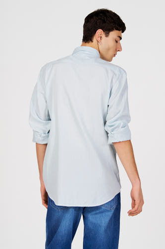 Blauw gestreept overhemd (lange mouwen) van Le Fabuleux Marcel de Bruxelles, met opgerolde mouwen, gedragen met een donkerblauwe jeans.
