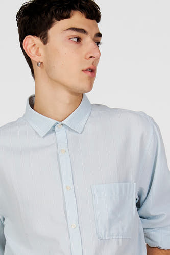 Chemise bleue à manches longues de Le Fabuleux Marcel de Bruxelles, avec fines rayures verticales et poche poitrine.