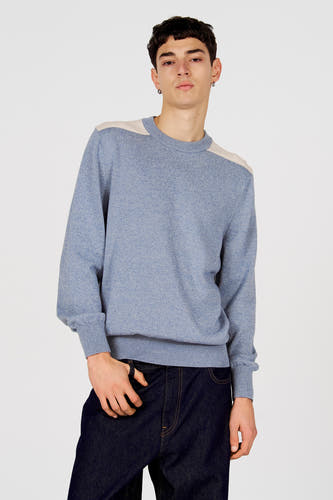 Pull bleu à col rond de Le Fabuleux Marcel de Bruxelles, avec des accents blanc cassé sur les épaules, combiné avec un jean foncé.