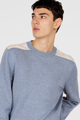 Pull bleu à col rond de Le Fabuleux Marcel de Bruxelles, avec des accents beiges sur les épaules.