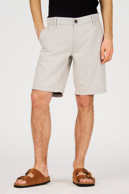 Short écru de Le Fabuleux Marcel de Bruxelles, vu de dos, avec poches latérales et sandales marron.