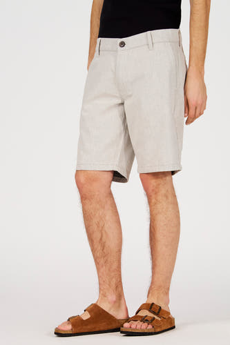 Short écru de Le Fabuleux Marcel de Bruxelles, avec une texture subtile et une coupe décontractée, porté avec des sandales marron.