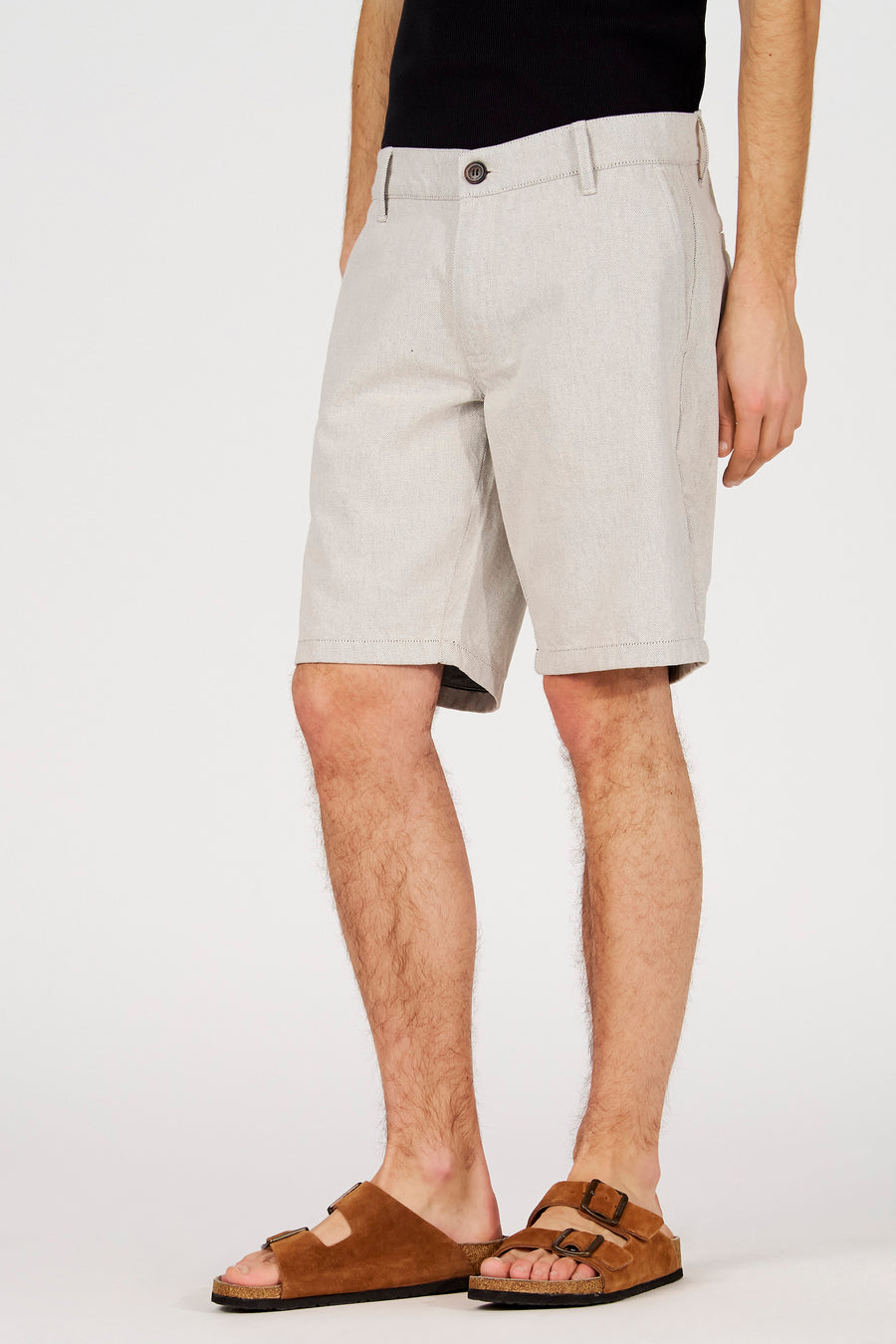 Short écru de Le Fabuleux Marcel de Bruxelles, avec une texture subtile et une coupe décontractée, porté avec des sandales marron.