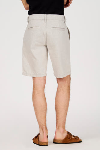 Short écru de Le Fabuleux Marcel de Bruxelles, avec une texture subtile et des sandales marron.