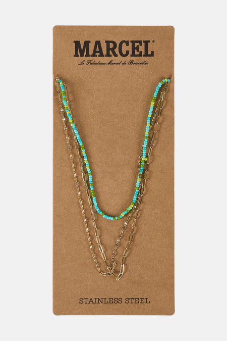 Gouden kettingen met blauwe en groene kralen op een bruin kartonnen etiket.