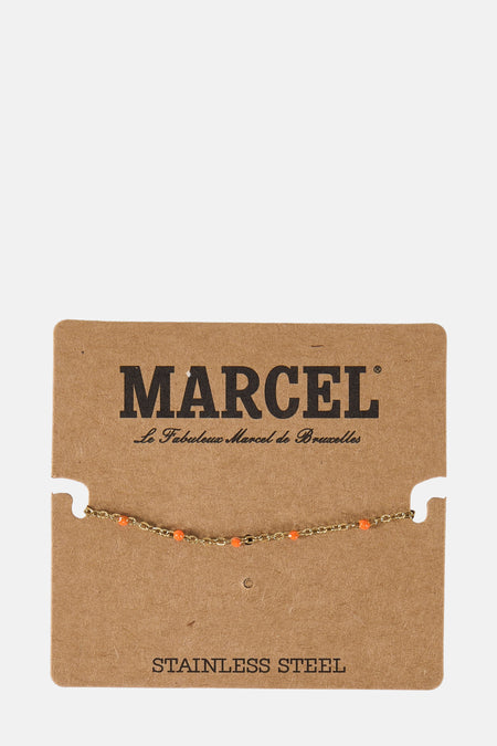 Gouden armband met oranje kralen op bruin karton met "MARCEL" en "STAINLESS STEEL" tekst.