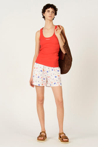 Débardeur côtelé rouge de Le Fabuleux Marcel de Bruxelles, vue arrière sur femme aux cheveux courts et bouclés et short imprimé.