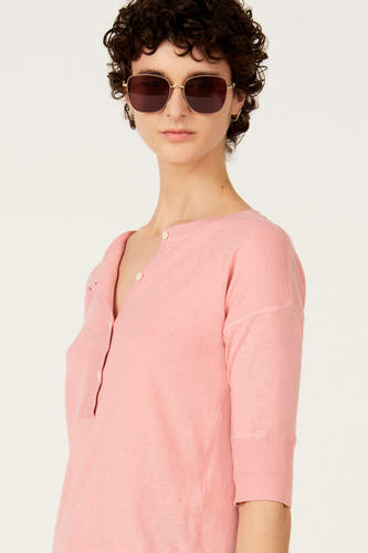 Roze trui met ronde hals van Le Fabuleux Marcel de Bruxelles, met knoopjes en gedragen met een zonnebril.