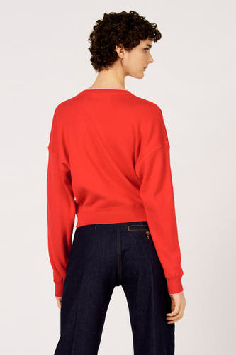 Rode trui met ronde hals van Le Fabuleux Marcel de Bruxelles, gezien van achteren, gecombineerd met donkere, wijde broek.