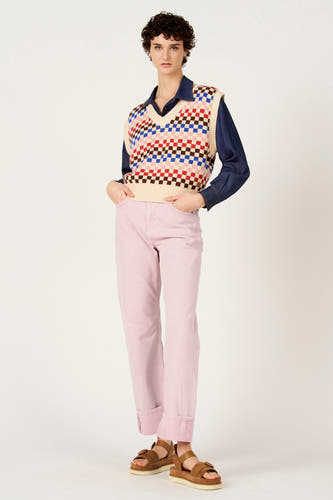 Débardeur multicolore de Le Fabuleux Marcel de Bruxelles, à motif à carreaux, porté sur une blouse en jean et un pantalon rose.