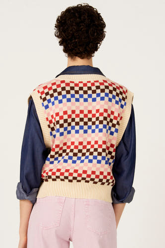 Multikleurige debardeur van Le Fabuleux Marcel de Bruxelles met een dambordpatroon, gedragen over een denim overhemd en met een roze broek.
