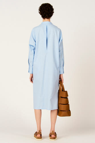 Robe bleue à manches longues de Le Fabuleux Marcel de Bruxelles, avec fermeture à boutons et un sac marron.