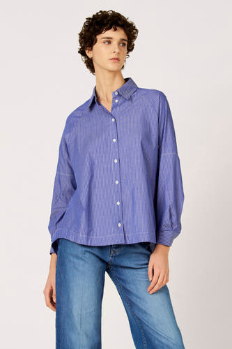 Chemise bleue à manches longues de Le Fabuleux Marcel de Bruxelles, avec un motif à rayures verticales, portée avec un jean.