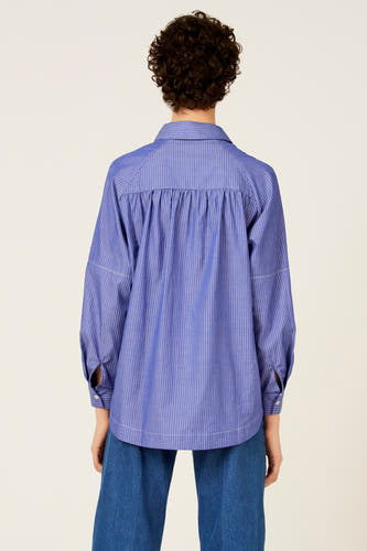 Chemise bleue à rayures à manches longues de Le Fabuleux Marcel de Bruxelles, vue de dos, avec détails plissés et pantalon bleu.