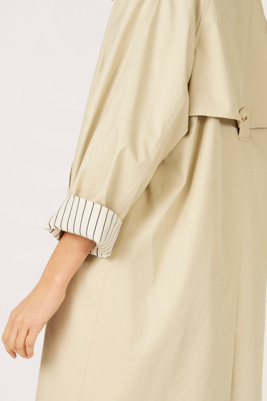 Long manteau beige de Le Fabuleux Marcel de Bruxelles, avec doublure rayée au niveau des manches.