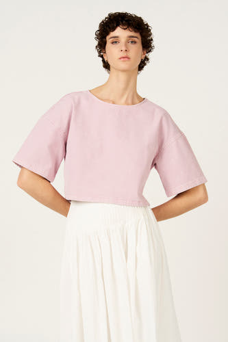 Chemisier rose à manches courtes de Le Fabuleux Marcel de Bruxelles, avec une coupe courte et une jupe blanche.