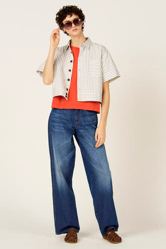 Chemise bleue à rayures à manches courtes de Le Fabuleux Marcel de Bruxelles, portée avec un t-shirt orange et un jean ample.