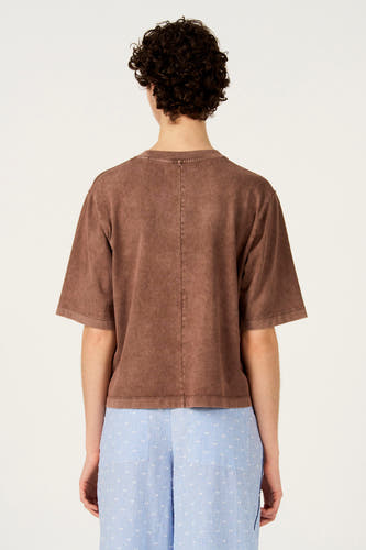 T-shirt marron à manches courtes de Le Fabuleux Marcel de Bruxelles, avec une texture délavée, porté avec un pantalon rayé.