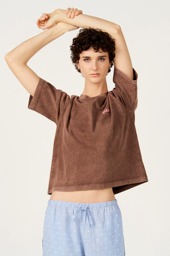 T-shirt marron à manches courtes de Le Fabuleux Marcel de Bruxelles, avec un léger délavage vintage et porté avec un pantalon rayé.