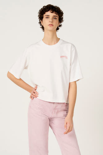 T-shirt blanc à manches courtes de Le Fabuleux Marcel de Bruxelles, porté avec un jean rose.