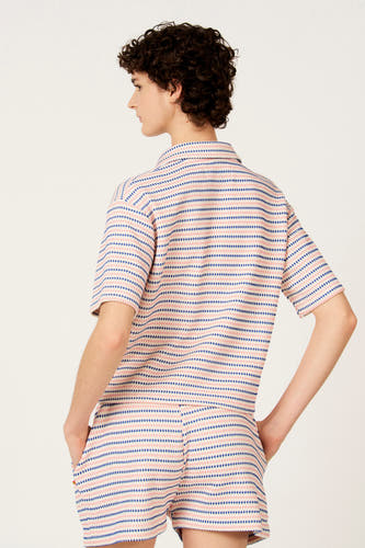 Blauwe polo van Le Fabuleux Marcel de Bruxelles, met roze strepen en een diamantpatroon, van achteren gezien.
