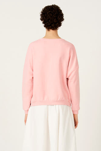 Roze sweater met ronde hals van Le Fabuleux Marcel de Bruxelles, rugaanzicht met witte rok.
