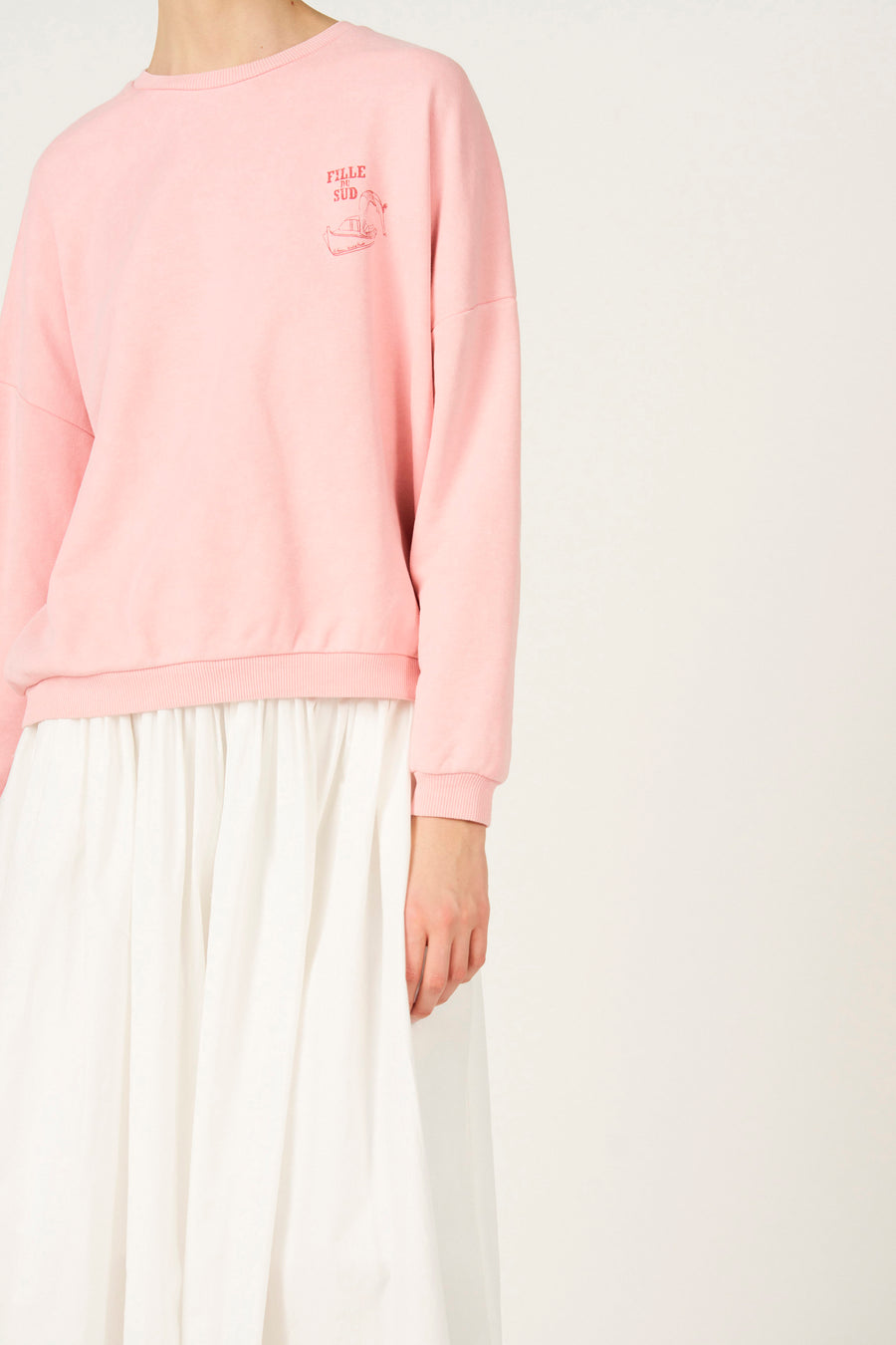 Pull rose de Le Fabuleux Marcel de Bruxelles, avec un petit imprimé rouge et combiné avec une jupe blanche.