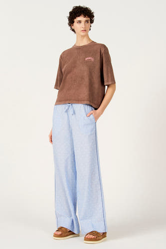 Pantalon bleu à pois de Le Fabuleux Marcel de Bruxelles, avec une coupe ample et des sandales marron.