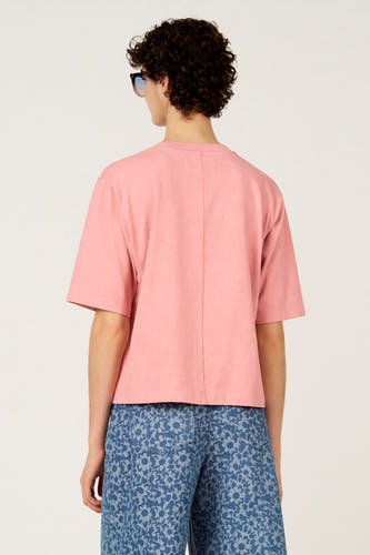T-shirt rose à manches courtes de Le Fabuleux Marcel de Bruxelles, vu de dos, avec un jean à motif floral.