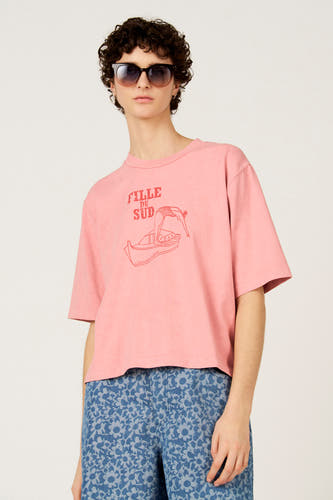 T-shirt rose à manches courtes de Le Fabuleux Marcel de Bruxelles, avec un imprimé vintage d'une femme dans un bateau.