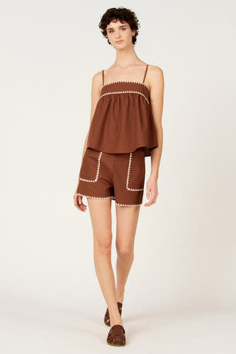 Chemisier marron ample de Le Fabuleux Marcel de Bruxelles, avec des détails zigzag blancs le long de l'encolure, associé à un short marron et des sandales.