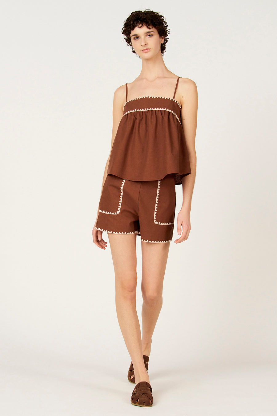 Short marron de Le Fabuleux Marcel de Bruxelles, avec des poches plaquées bordées de surpiqûres zigzag blanches.