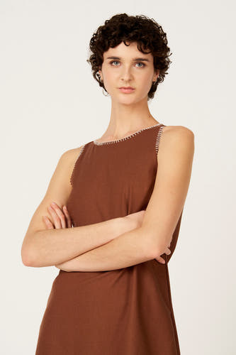 Robe sans manches marron, de Le Fabuleux Marcel de Bruxelles, avec surpiqûres blanches le long de l'encolure et des emmanchures.