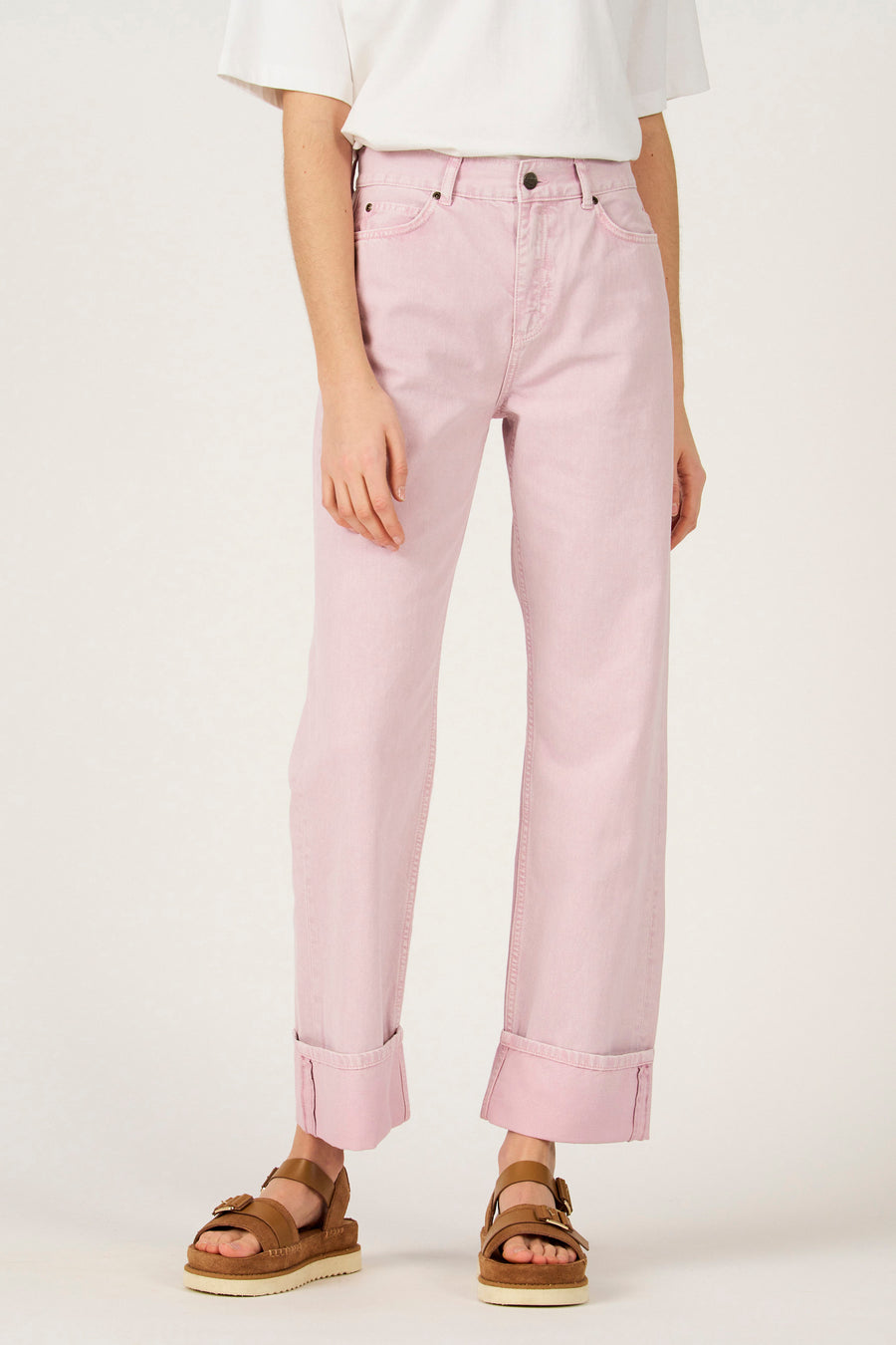 Pantalon rose de Le Fabuleux Marcel de Bruxelles, avec des jambes retroussées et des sandales marron.