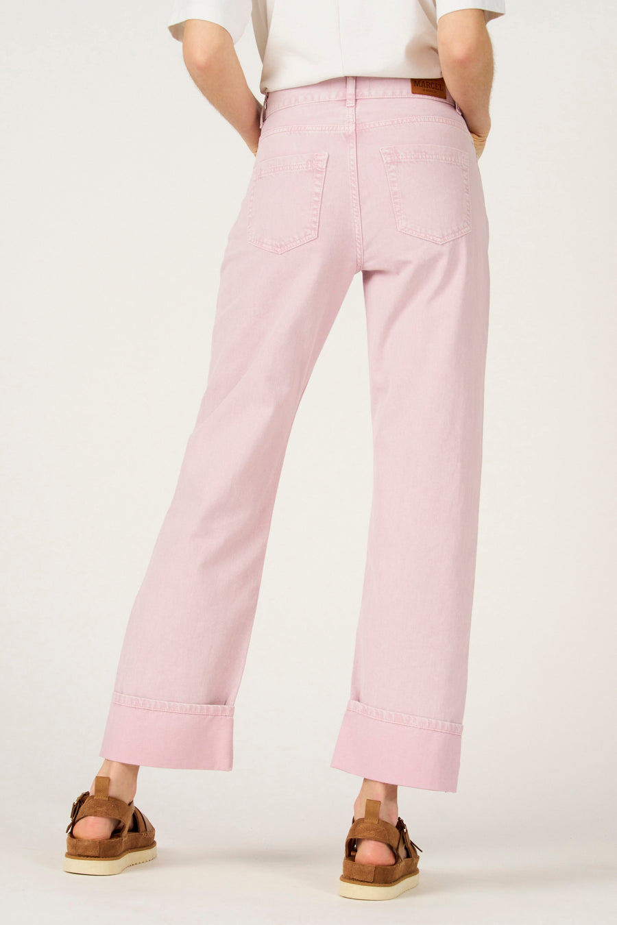 Roze colorbroek van Le Fabuleux Marcel de Bruxelles, met opgerolde pijpen en bruine sandalen.
