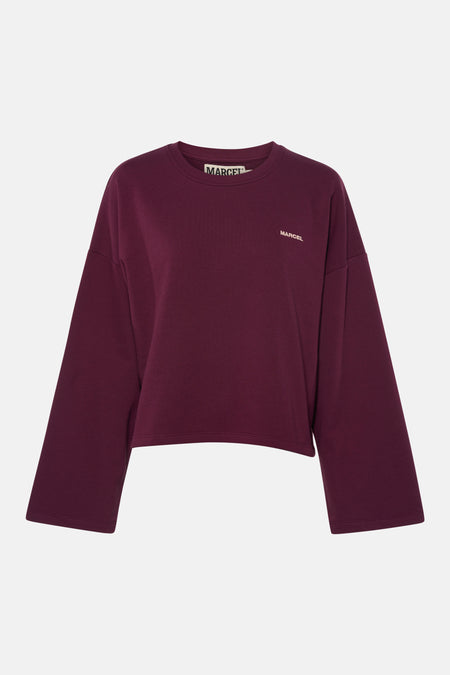 Pull violet à col rond de Le Fabuleux Marcel de Bruxelles, avec inscription 'MARCEL' marron clair sur la poitrine et une étiquette logo noir et blanc dans le cou.