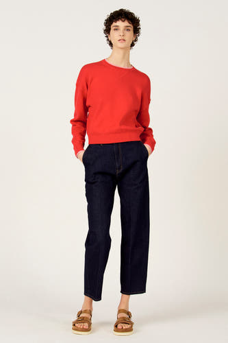 Jean slim en denim bleu foncé de Le Fabuleux Marcel de Bruxelles, combiné avec un pull rouge et des sandales marron.