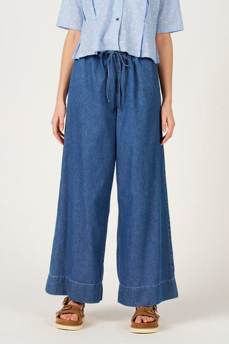 Wijde jeans van blauw denim, van Le Fabuleux Marcel de Bruxelles, met een hoge taille en sandalen met bandjes.
