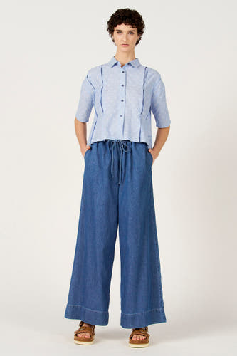 Jeans larges en denim bleu moyen de Le Fabuleux Marcel de Bruxelles, avec cordon de serrage et sandales marron.