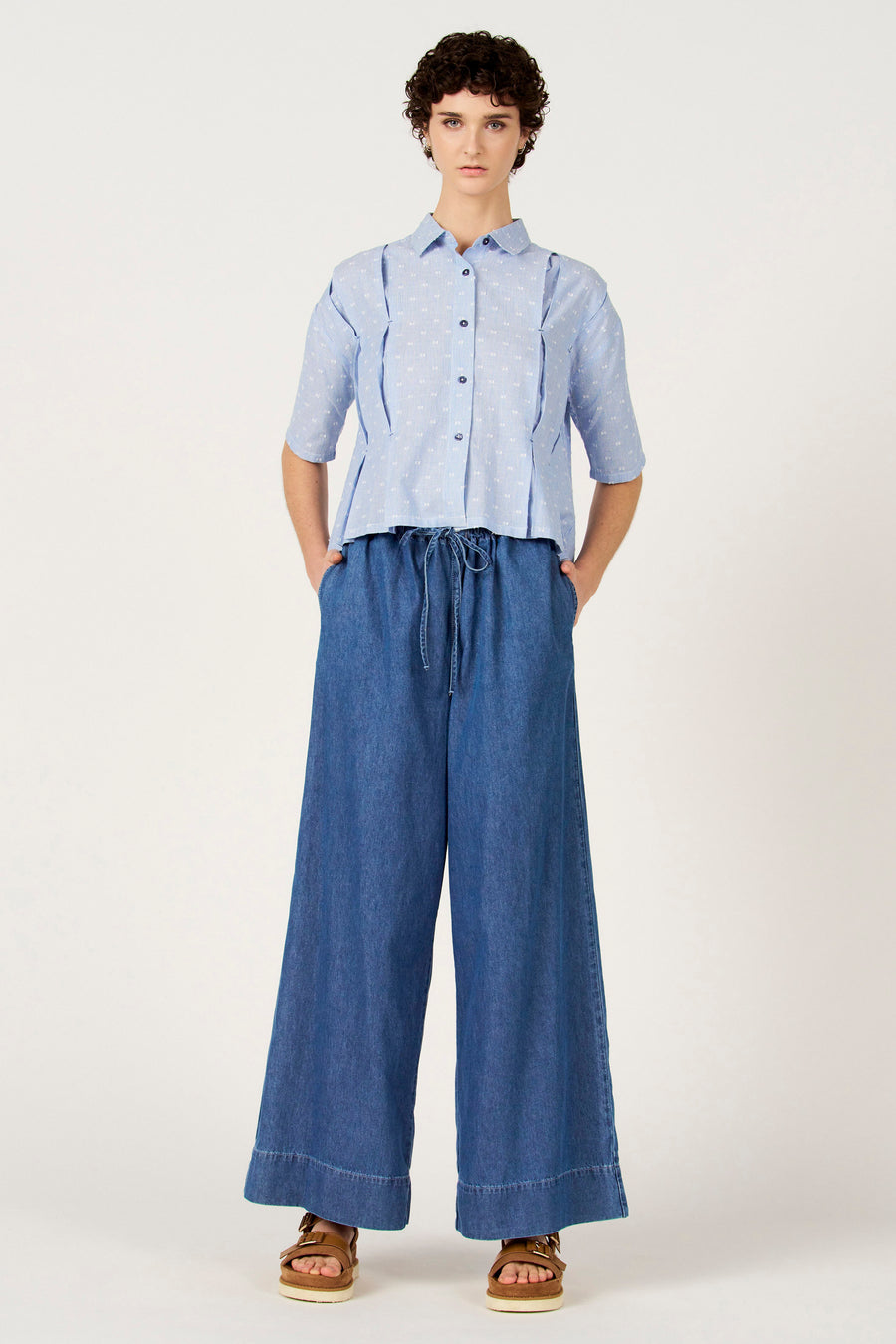 Jeans larges en denim bleu moyen de Le Fabuleux Marcel de Bruxelles, avec cordon de serrage et sandales marron.