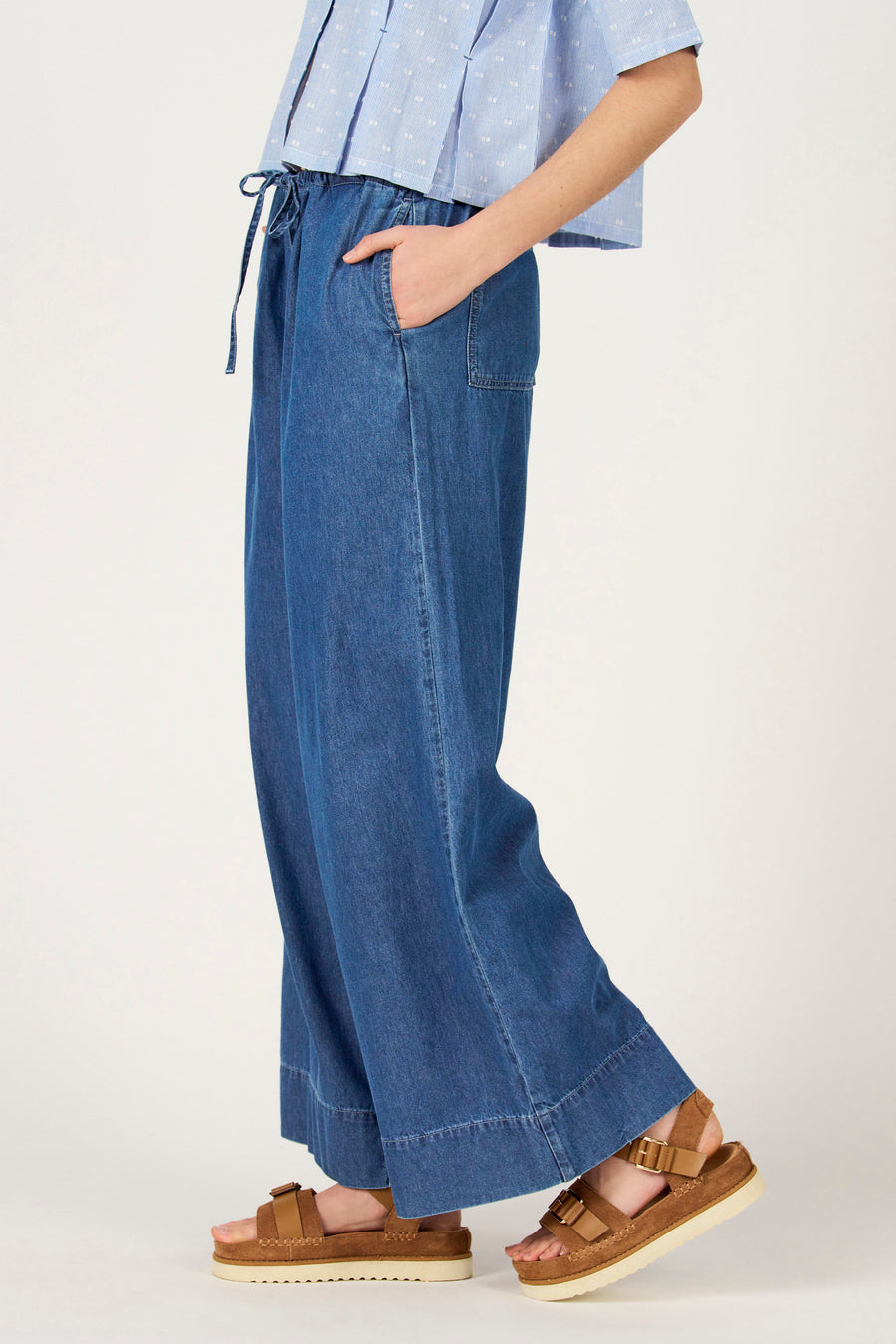 Jeans larges en denim bleu moyen de Le Fabuleux Marcel de Bruxelles, avec cordon de serrage et sandales marron.