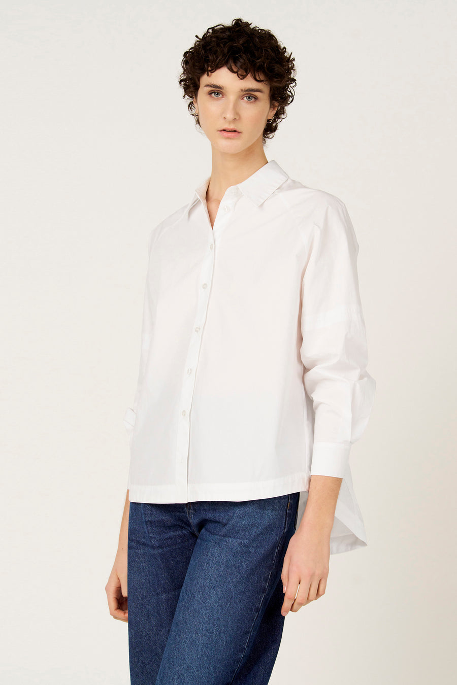 Chemise blanche à manches longues de Le Fabuleux Marcel de Bruxelles, portée avec un jean foncé.