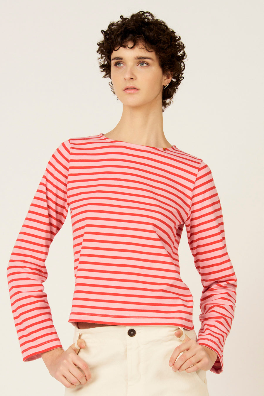 T-shirt à manches longues rayé rouge-rose de Le Fabuleux Marcel de Bruxelles, vu de dos, porté avec un pantalon de couleur crème.